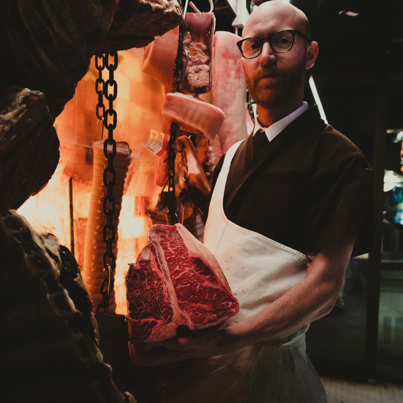 A butcher trimming a cut of beef on a block